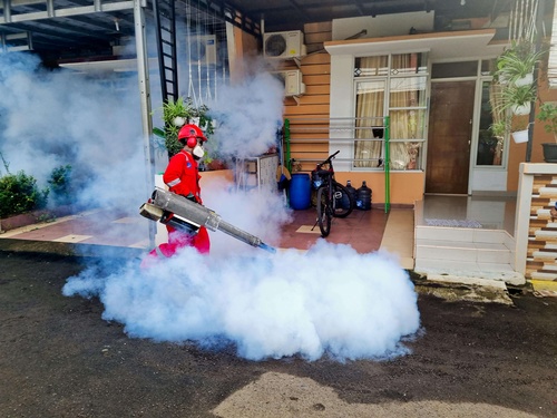 Pest control worker in red uniform using fogging machine to spray insecticide in residential area to prevent dengue and Zika outbreaks.5dmapluscompany